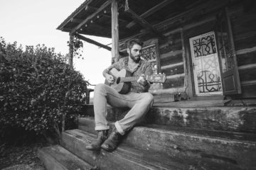 Tyler Key playing guitar on a porch