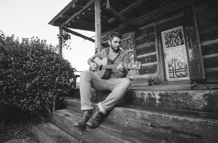 Tyler Key playing guitar on a porch