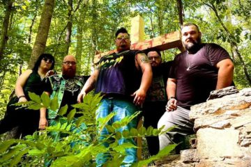 Blood Oaks standing in front of a wood cross with blood on it