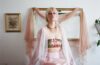 Julianna Money sitting on a bed with a mirror and painting behind them