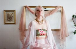 Julianna Money sitting on a bed with a mirror and painting behind them