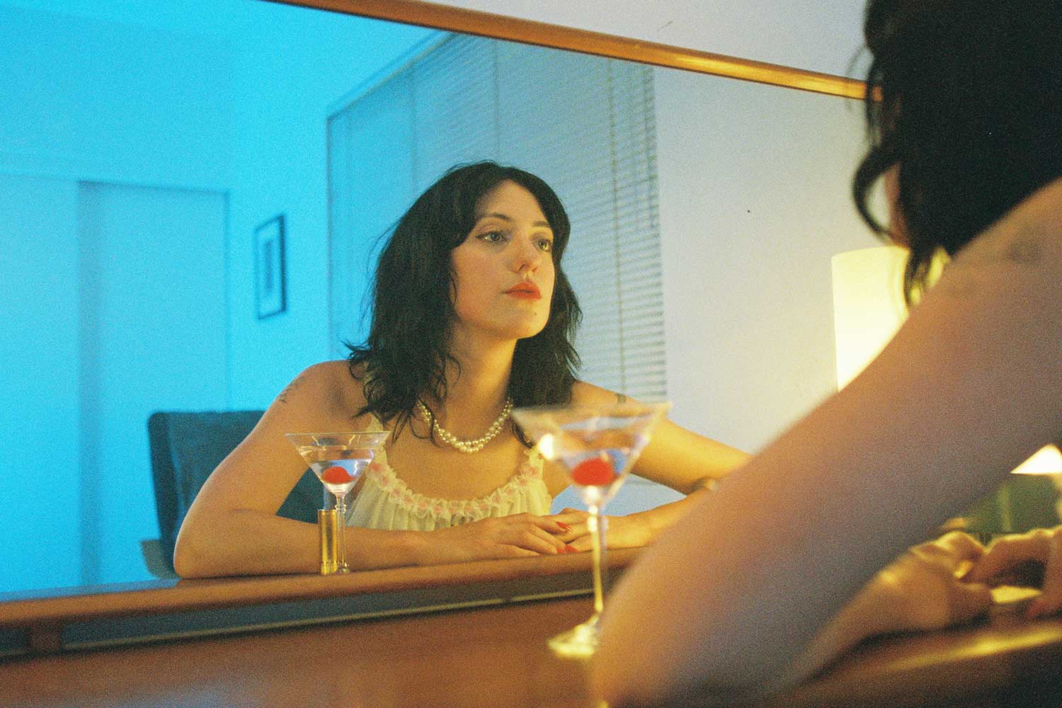 Grace Bellury of Karaoke with a cocktail staring into a mirror