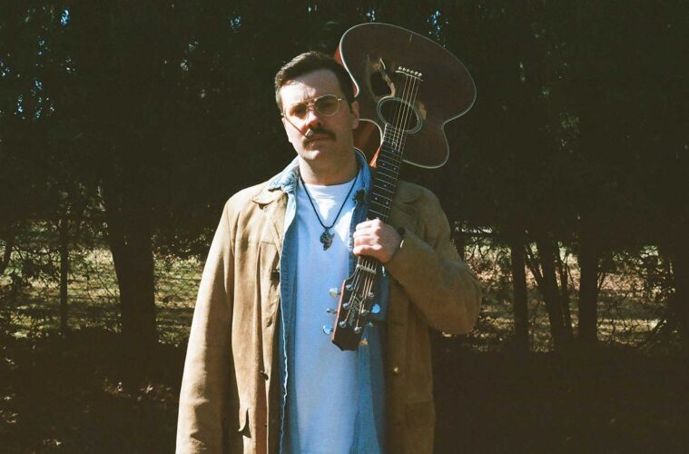 Brian Revels with an acoustic guitar flung over his shoulder