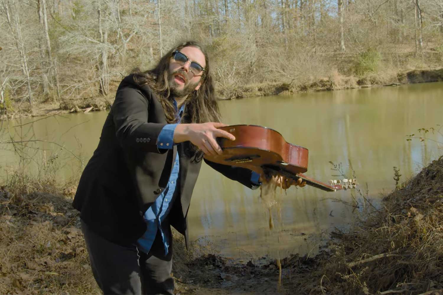 Tyler Key dumping water out of an acoustic guitar on the Oconee River