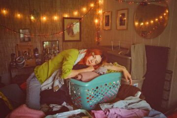 Sydney Ward of Sleepers Club leaning on a blue laundry basket