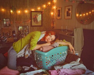 Sydney Ward of Sleepers Club leaning on a blue laundry basket