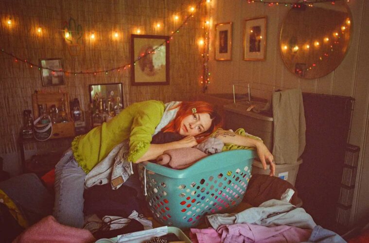 Sydney Ward of Sleepers Club leaning on a blue laundry basket