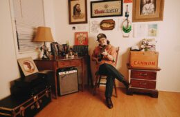 Cannon Rogers playing an acoustic guitar in his office