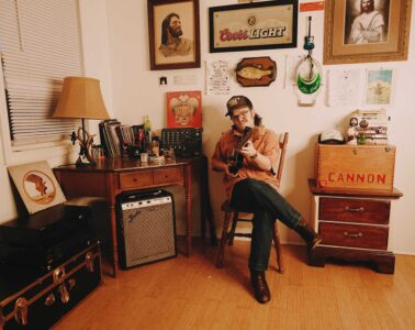 Cannon Rogers playing an acoustic guitar in his office