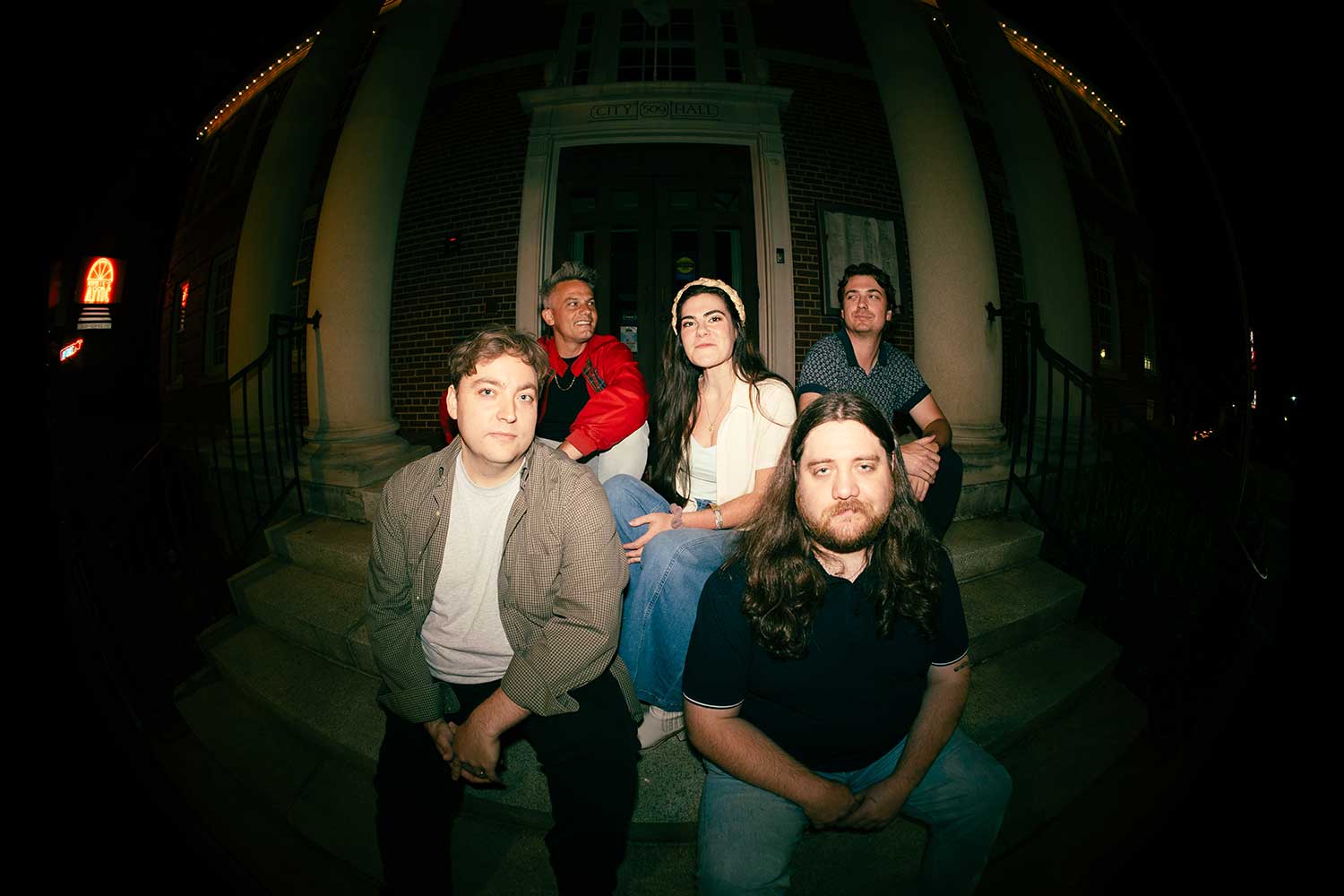 members of Flat Tired siiting on the front steps of a house